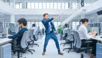 Young Cheerful Handsome Business Manager Wearing a Suit and Tie is Dancing like Crazy in the Office. Diverse and Motivated Business People Work on Computers in Modern Open Office.